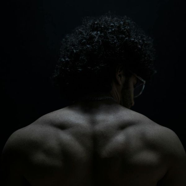 A man in a focused plank position in a minimalist dark gym.